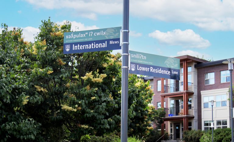 International Mews street sign on UBC Okanagan campus with blue sky and residences in the background.